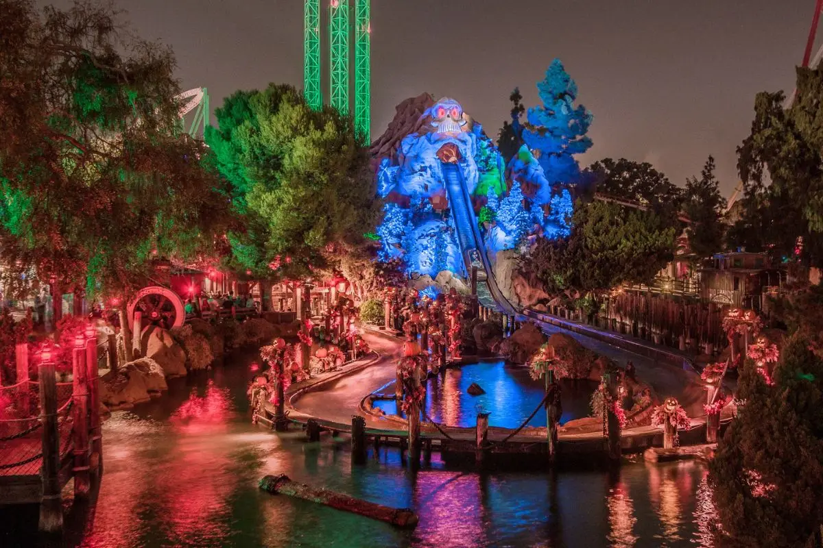 One of the rides at Knott’s Scary Farm with Halloween decorations and glowing lights at night , creating a spooky atmosphere