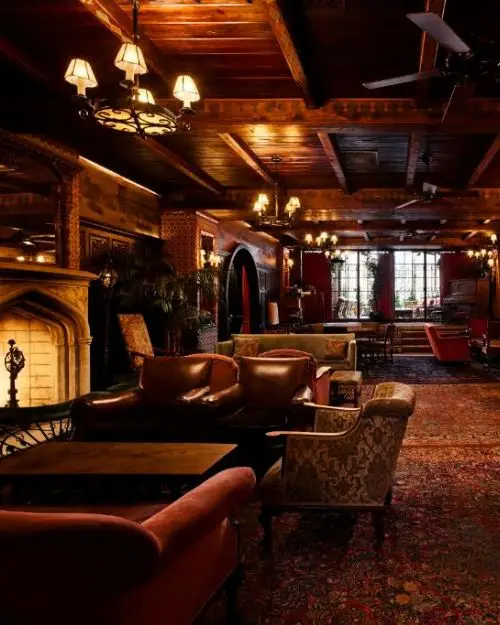 A dim lobby with leather furnishings and wooden walls, with a cozy, spooky but upscale vibe