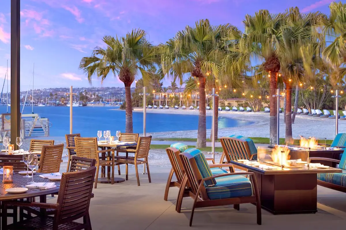 A waterfront restaurant with seating around firepits on the water at the Bahia Resort, showing that its one of the best places to travel in December