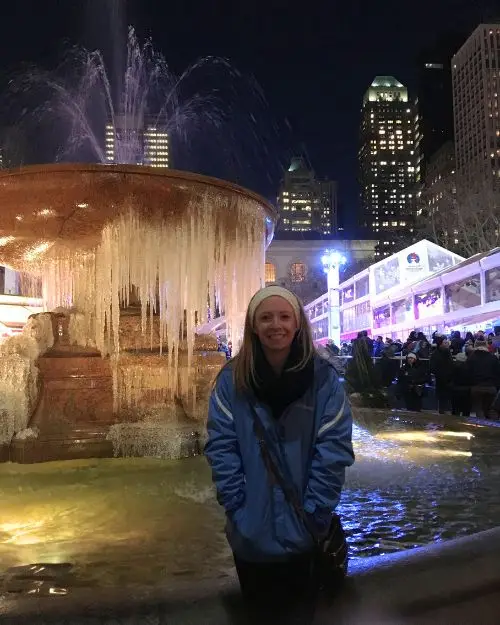 Lauren of Inspired Backpacker standing in front of a half frozen fountain at Bryant Park Holiday Market