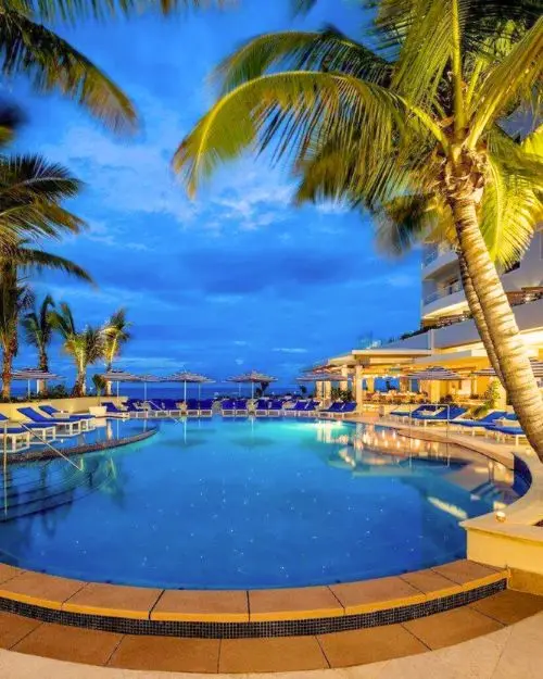A pool and palm trees under a sunsetting evening sky at one of the best hotels in Puerto Rico, the Condado Vanderbilt hotel