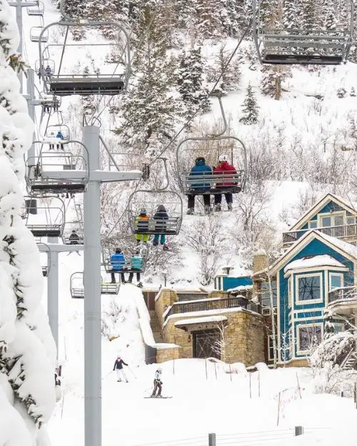 People riding up one of the ski lifts in Park City with an abundance of snow, to show that it's a magical destination and one of the best places to travel in December in the USA for snow