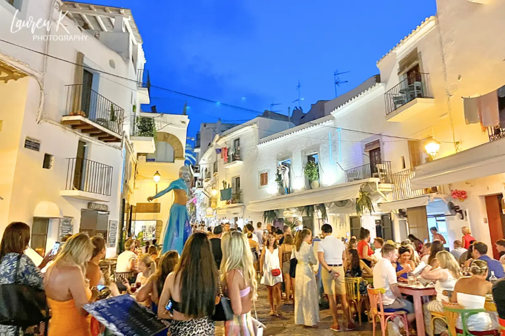 Cover image for the where to stay in Ibiza Spain blog which shows the bustling Old Town area lit up at night with lots of people