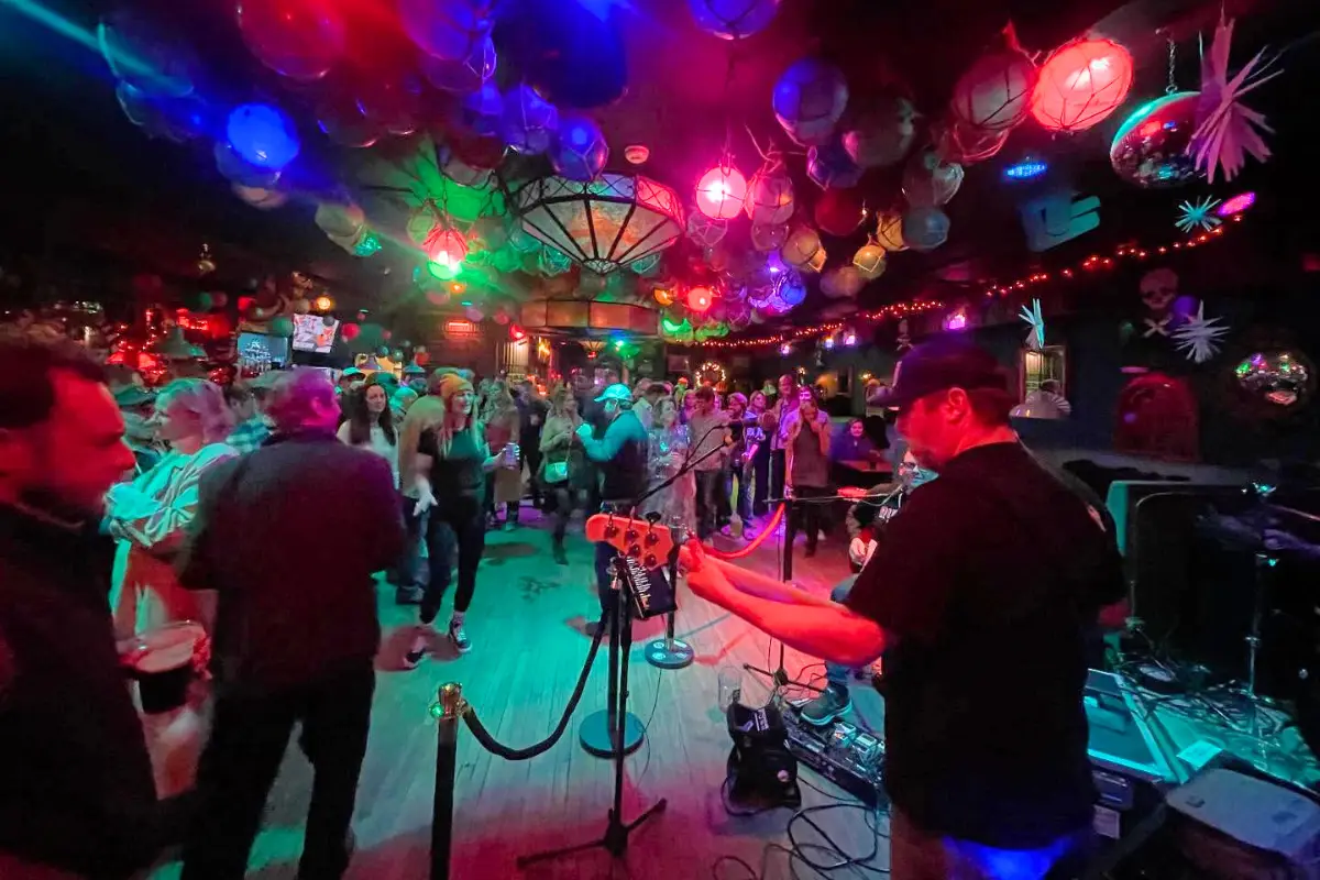 Band under neon lights and a packed bar at Bounty Bar 