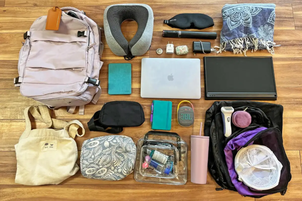 Cover image for the digital nomad gear packing list blog which shows a bunch of items set out on the floor that digital nomads should pack