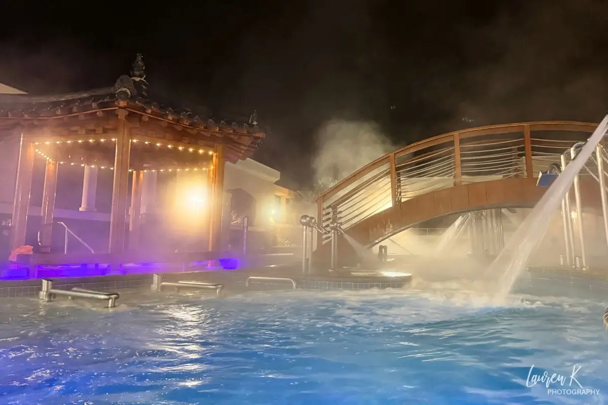 Cover image for the King Spa Chantilly review blog which shows the outdoor spa pool at night lit up with neon lights and mist coming off the water