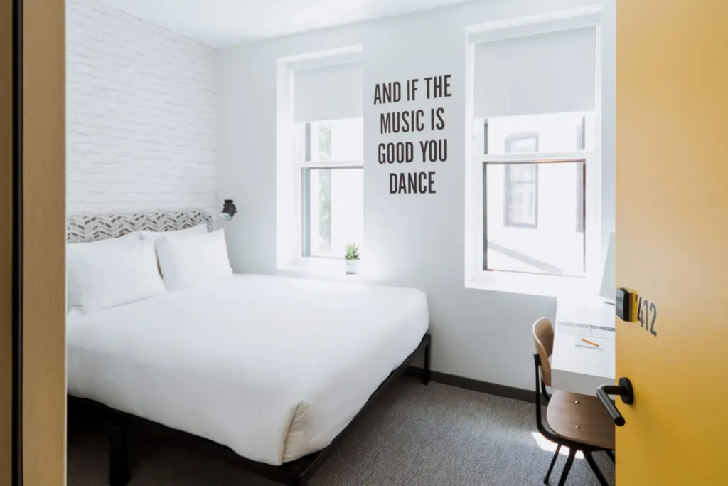 A small basic room with white walls and a bed and desk