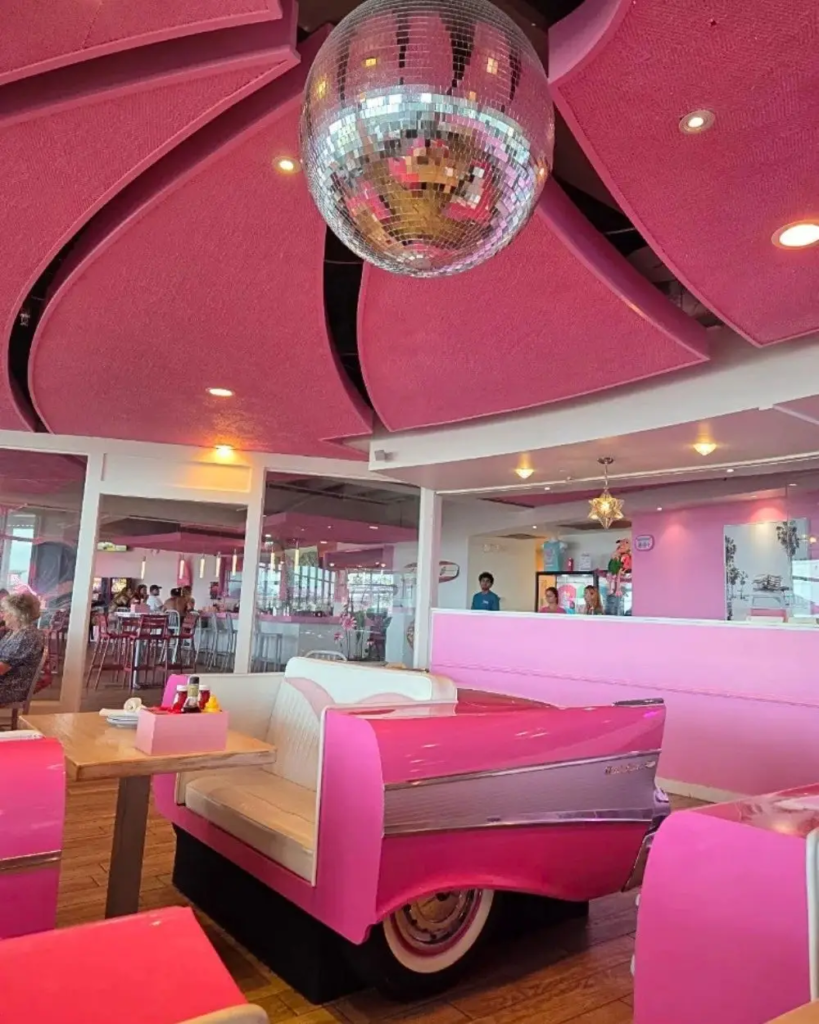 Bright pink interior of a restaurant with a disco ball and pink convertible style table below