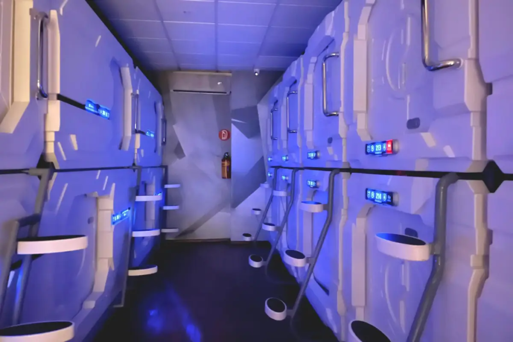 Cover image for the pros and cons of capsule hotels blog which shows pods in a dimly lit room with purple backlighting