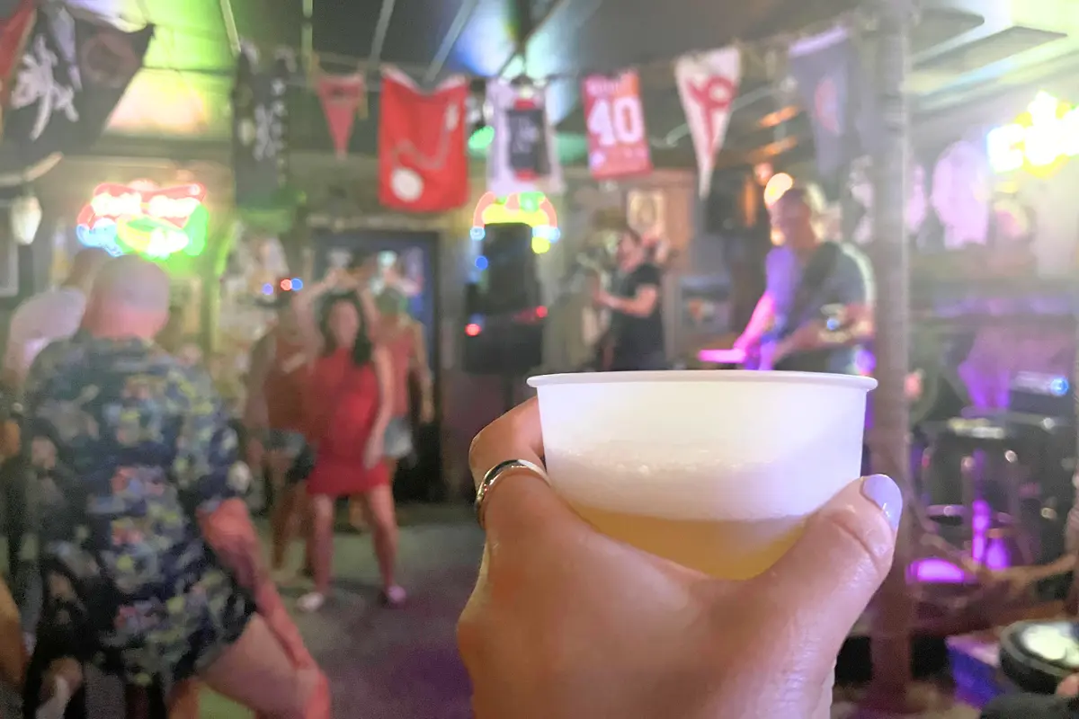 Woman holding a beer at the Saltwater Hippie bar with a band playing