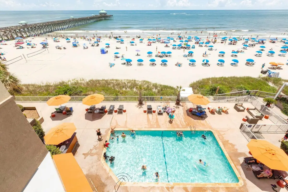 The Tides hotel at the Folly Beach oceanfront on a sunny day with people enjoying the pool and ocean in the background