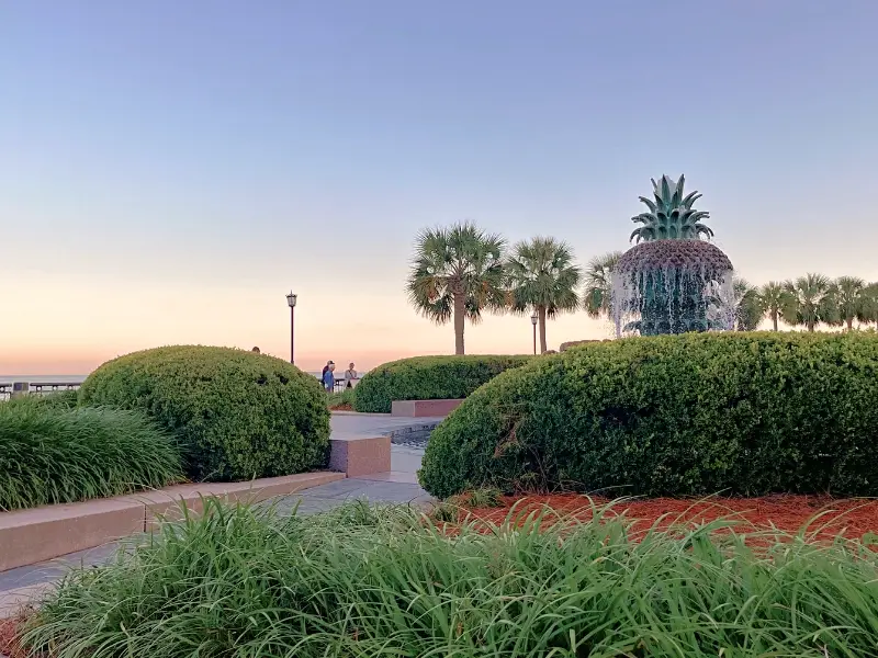 Pineapple fountain in Charleston under a sunsetting sky at waterfront park, taken by Lauren Kessel of Inspired Backpacker travel blog